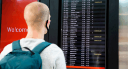 A traveller looks at an airport board showing several cancelled flights.