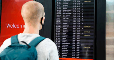 A traveller looks at an airport board showing several cancelled flights.