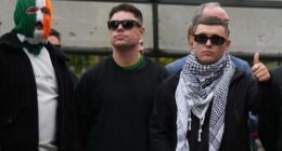 Liam Ã“g Ã“ hAnnaidh, aka Mo Chara, right, a member of the Irish language band Kneecap, celebrates as he leaves Woolwich Crown Court in London, Friday, Sept. 26, 2025, after Chief Magistrate, Senior District Judge Paul Goldspring, dismissed a terrorism offence relating to displaying a flag in support of Hezbollah during a performance with the band in November 2024, on a technical error.