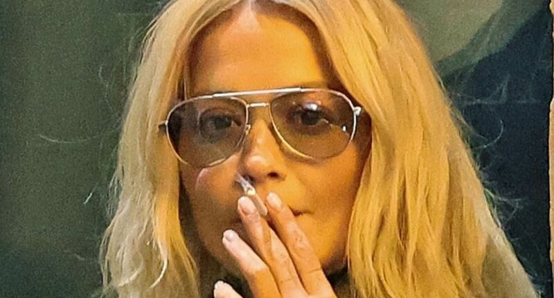 Rita Ora lights up a cigarette outside her hotel after the Prada show