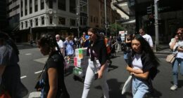 Pedestrians move across Market Street in Sydney, Australia.