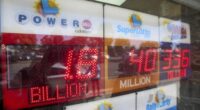 An electronic sign reads $1.8 billion as crowds wait in line to buy lottery tickets at the Bluebird Liquor store in Hawthorne, Calif., on Friday, Sept. 5, 2025. (AP Photo/Damian Dovarganes)