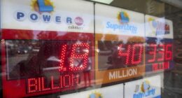 An electronic sign reads $1.8 billion as crowds wait in line to buy lottery tickets at the Bluebird Liquor store in Hawthorne, Calif., on Friday, Sept. 5, 2025. (AP Photo/Damian Dovarganes)