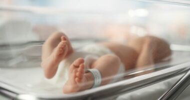 Cute Little Caucasian Newborn Baby Lying in Bassinet in a Maternity Hospital. Portrait of a Tiny Playful and Energetic Child with a Name ID Tag on the Leg. Healthcare, Pregnancy and Motherhood Concept