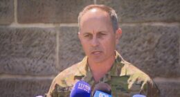 Brigadier Ben McLennan speaking at a press conference in his uniform.