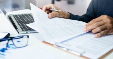 businessman reviewing document reports at office workplace with computer laptop. legal expert, professional lawyer reading and checking financial documents or insurance contract