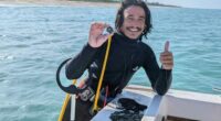In this undated photo provided by shipwreck salvage company 1715 Fleet- Queens Jewels, LLC, diver Levin Shavers shows coins uncovered from a Spanish shipwreck off the Atlantic coast of Florida.