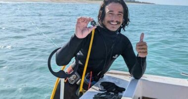 In this undated photo provided by shipwreck salvage company 1715 Fleet- Queens Jewels, LLC, diver Levin Shavers shows coins uncovered from a Spanish shipwreck off the Atlantic coast of Florida.