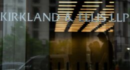 Signage for Kirkland & Ellis LLP is displayed on the glass entrance of a building, with people visible in silhouette inside.