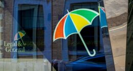 Legal & General logo with a multicolored umbrella is reflected on the glass of the headquarters building in London.