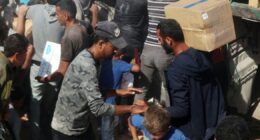 Palestinians crowd onto aid trucks moving through Gaza