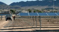 John Gatlin of Greenbotics walks between rows of solar panels at a solar generating station, with a truck nearby.