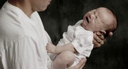 A father is holding his crying baby boy.