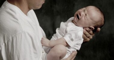 A father is holding his crying baby boy.