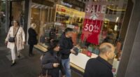 Shoppers walk past a sale sign in a Melbourne shopping centre.