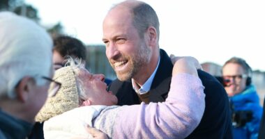 Prince William braves a chilly walk down memory lane on the beach in North Wales where he worked as an RAF pilot