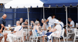 A group of grey-haired people dine at an outdoor cafe.