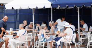 A group of grey-haired people dine at an outdoor cafe.
