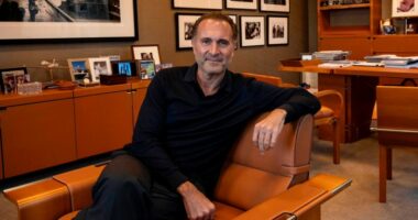 Gerry Cardinale sits in a brown leather chair in an office decorated with framed photos and shelves of memorabilia.