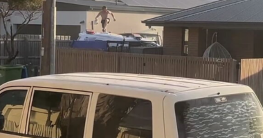 The man was seen leaping from the top of the police car onto the footpath as he fled the scene.