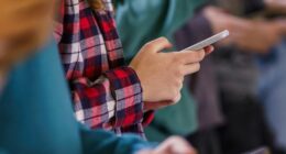Close-up group of teenagers using mobile phones in school corridor