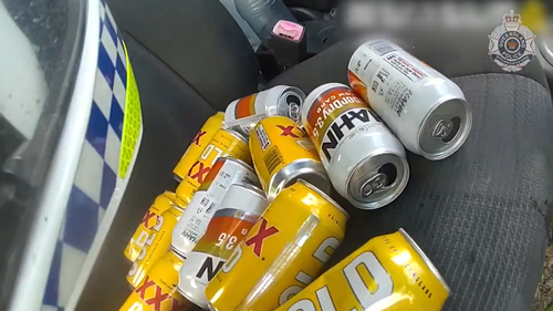 The officer found more than a dozen empty cans of beer under the driver's seat of the red Suzuki.