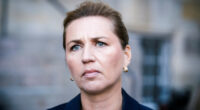 Mette Frederiksen appears serious while giving a press statement.