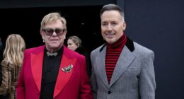 Elton John is aided by David Furnish as he heads to Valentino's show