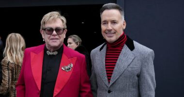 Elton John is aided by David Furnish as he heads to Valentino's show