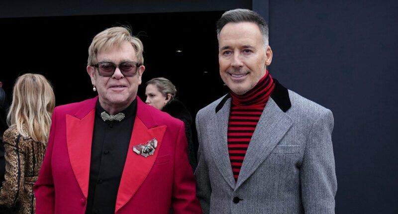 Elton John is aided by David Furnish as he heads to Valentino's show
