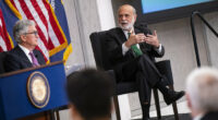 Ben Bernanke gestures while speaking with Jerome Powell during a conference in 2023.