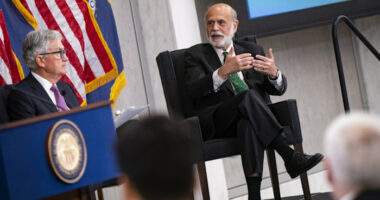 Ben Bernanke gestures while speaking with Jerome Powell during a conference in 2023.