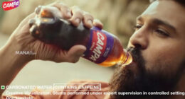 A still of a Campa Cola advertisement depicting a bearded Bollywood actor drinking a bottle of Campa Cola