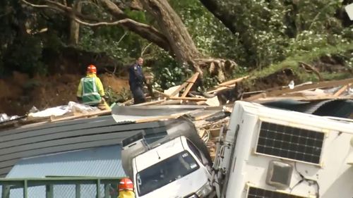 In this image from a video, a police officer with dog searches people near the site of a landslide at the base of Mount Maunganui on New Zealands North Island Thursday, Jan. 22, 2026.