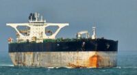 Oil tanker Bella 1 at sea, showing rust stains and large white superstructure, as seen in the Singapore Strait.