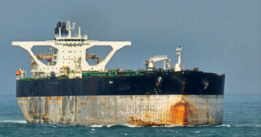 Oil tanker Bella 1 at sea, showing rust stains and large white superstructure, as seen in the Singapore Strait.