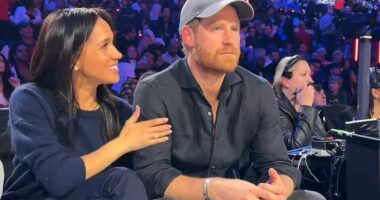 Meghan can't keep her hands off her 'forever Valentine' Harry as she encourages her Prince to smile for the cameras during NBA date night