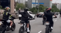 Group of young people riding e-bikes in Sydney peak hour traffic.
