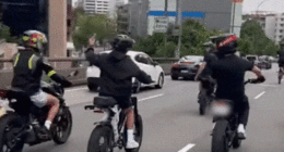 Group of young people riding e-bikes in Sydney peak hour traffic.