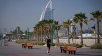 A man jogs along a beach with the Burj Al Arab luxury hotel seen in the background in Dubai, United Arab Emirates, Sunday, March 1, 2026.