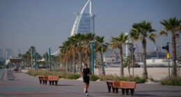 A man jogs along a beach with the Burj Al Arab luxury hotel seen in the background in Dubai, United Arab Emirates, Sunday, March 1, 2026.