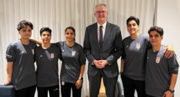 In this photo supplied by Australia's Minister for Home Affairs Tony Burke's office, the Minister Tony Burke, center, poses in an undisclosed location with five Iranian women soccer players who have been granted asylum in Australia, Tuesday, March 10, 2026. (Australia Ministry of Home Affairs via AP)