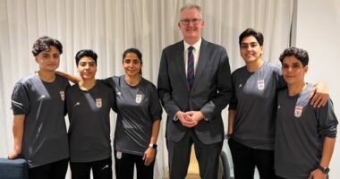 In this photo supplied by Australia's Minister for Home Affairs Tony Burke's office, the Minister Tony Burke, center, poses in an undisclosed location with five Iranian women soccer players who have been granted asylum in Australia, Tuesday, March 10, 2026. (Australia Ministry of Home Affairs via AP)