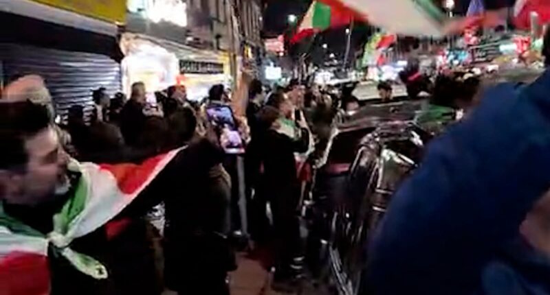 London street brought to a standstill as jubilant people blare music, hand out roses, and wave Iranian flags to celebrate the death of Ayatollah Ali Khamenei