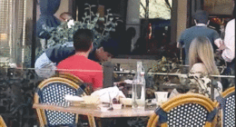 Two men appear to shove and lunge toward each other near an outdoor dining area