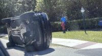 Golfer Tiger Woods stands by his overturned vehicle in Jupiter Island.