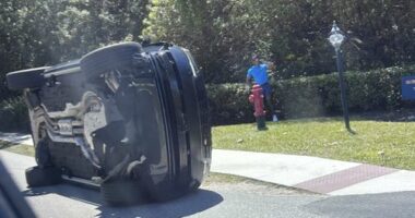 Golfer Tiger Woods stands by his overturned vehicle in Jupiter Island.