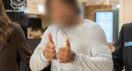 The man offered a thumbs-up sign to a camera at Sydney Airport.
