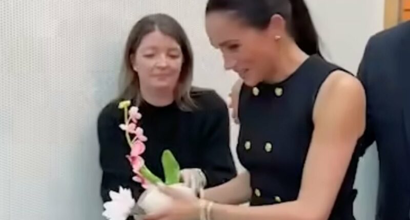 Just like a working royal! Moment Meghan hands gifted flowers to her aide during royal-style visit to children's hospital in Melbourne with Harry