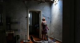 Zoya Shaposhnik 67 (left) looks up at the hole in her ceiling which was damaged this morning at approximately 9am in a missle strike where her ill husband (left) was sitting in their home in Krasnohorivka. Their roof and other parts of their home has been destroyed and Zoya has spent the day removing debris. Krasnohorivka, Ukraine. 16th June, 2022.
